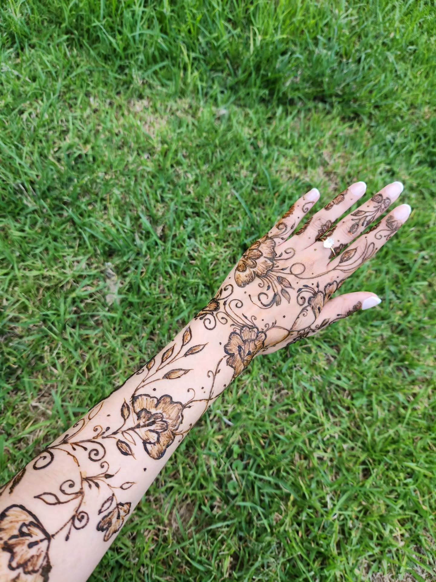 Floral vines from the hand up the arm, against grass