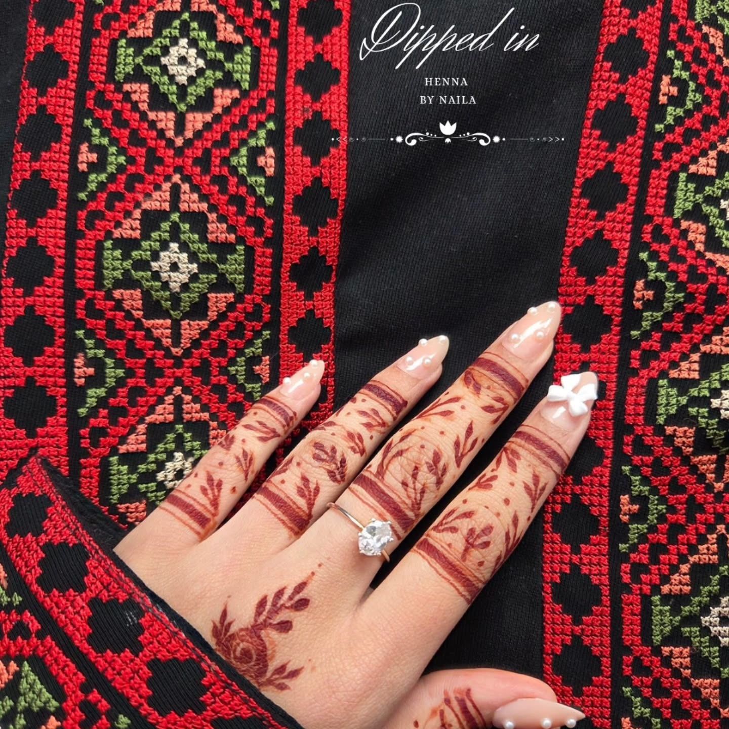 Delicate finger henna resting on red embroidered fabric